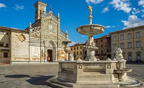 Prato Cathedral with its green and white marble facade, viewed from a sunny piazza with a fountain in the foreground.  - Prato Duomo 500x306 - Prato and Pistoia